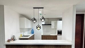 Eine moderne Küche mit einer zentralen Kochinsel, Barhocker und Pendelleuchten.