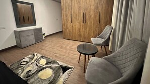 Ein modernes Wohnzimmer mit einer Couch, einem Sessel, einem Couchtisch und einem großen Kleiderschrank.