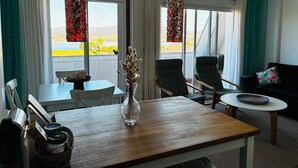 Habitación de hotel con una mesa de comedor, sillas, un sofá y vistas al exterior.