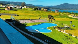 Una piscina de forma singular, rodeada por un césped cuidado y con vistas despejadas al mar y montañas distantes.