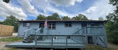 A two-story house with a front porch, a staircase, and an American flag.