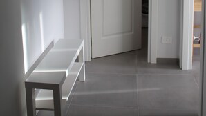 A hallway with a white bench, a door leading to another room, and framed pictures on the wall. - "Nicolini 39" Central, recently renovated, perfect for groups. (Napoli)