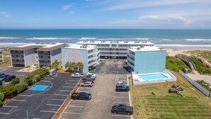 Un hotel con estacionamiento, cancha de baloncesto y zona de piscina.