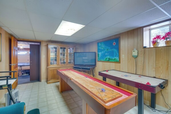Una habitación con una mesa de juego de raquetas, un televisor y un armario de madera.