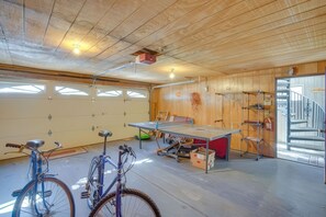 Eine Garage mit Tischtennisplatte, Fahrrädern und einer Treppe, die zu einer zweiten Etage führt.