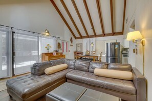 Ein modernes Wohnzimmer mit einem ledernen Ecksofa, einem Esstisch und einer Küchenzeile inklusive Kühlschrank.