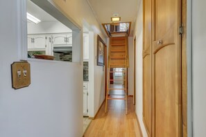 Ein schmales Treppenhaus mit Holzboden, einer Holztür rechts und einer Treppe, die zu einer oberen Ebene führt.