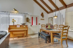 Ein gemütlicher Essbereich mit einem Holztisch, Stühlen und einem Klavier.