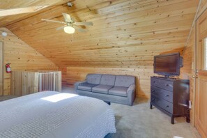 Ein gemütliches Schlafzimmer im Dachgeschoss mit einem Bett, einem Schlafsofa, einem Schminktisch und einem Fernseher.