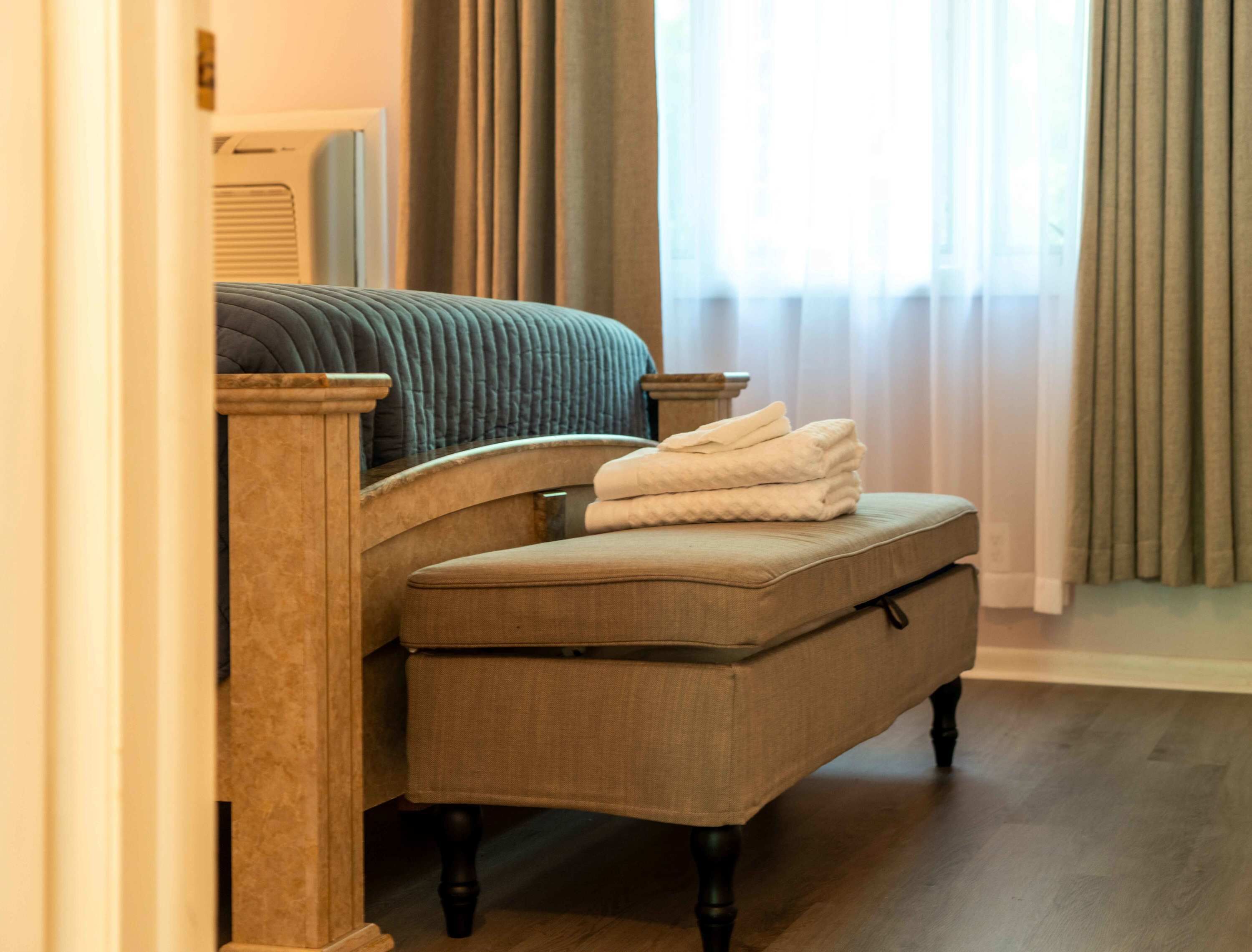 Una habitación de hotel con una cama, una silla y una pila de toallas.