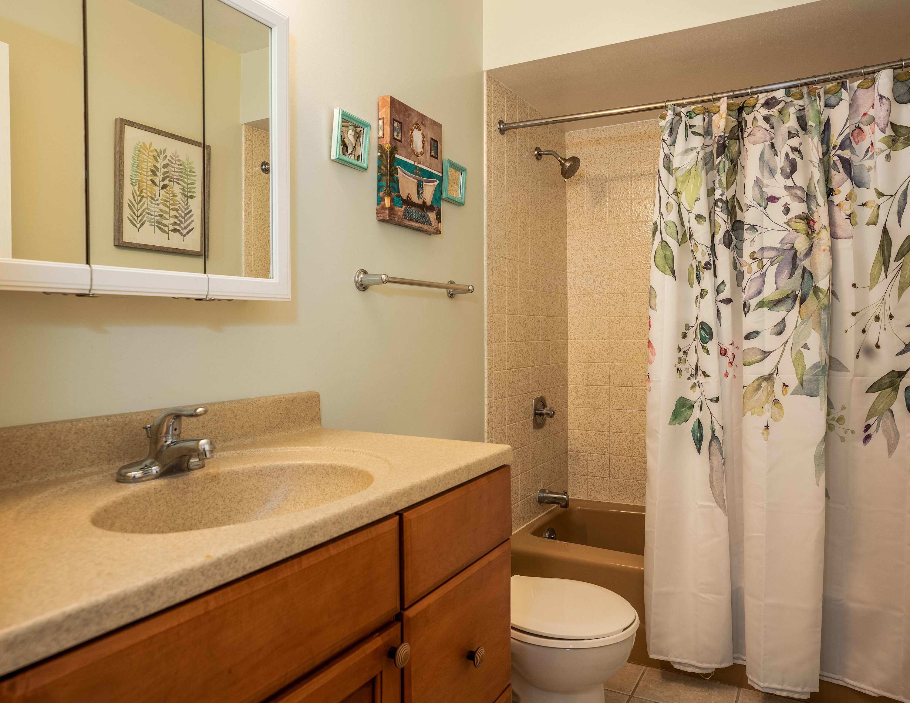 A bathroom with a sink, toilet, bathtub, and shower curtain.