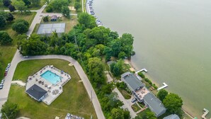 An aerial view of a lakeside property with a swimming pool, a dock, and a parking area. - Cozy Condo at Interlaken! Stay & Play on Lake Como (Lake Geneva)