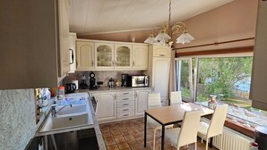 A kitchen with a sink, countertop, cabinets, and a dining area with chairs and a table. - Find tranquility and peace in this charming cottage in Lapscheure - Damme. (Damme)