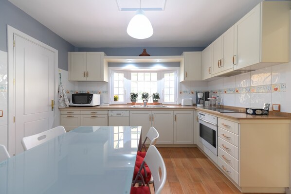 A kitchen with white cabinets, a microwave, a sink, and a dining table with chairs. - House in Santa Brigida With Sea & Mountain Views (Santa Brigida)