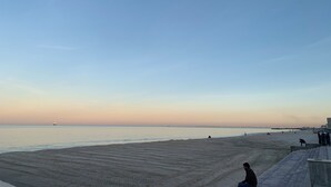 A beach with a clear sky, a sandy shore, and a few people. - Bel Appartement (Sousse)