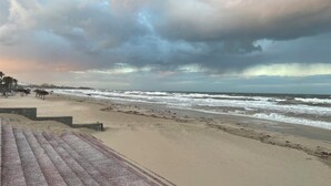 A beach with a paved walkway and umbrellas. - Bel Appartement (Sousse)