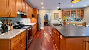 Una cocina con armarios de madera, electrodomésticos de acero inoxidable, encimera de mármol y una isla central.