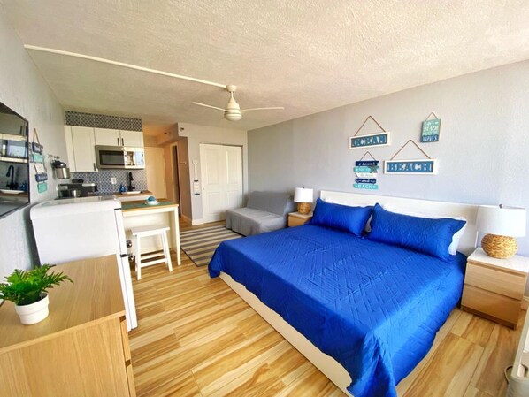 Ein gemütliches Schlafzimmer mit Bett, Nachttischen, Schreibtisch und einer Küchenzeile.