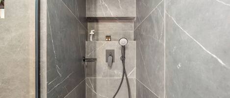 A modern shower area with a handheld showerhead, a control panel, and a soap dispenser.