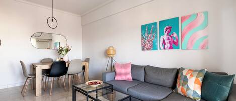 A modern living room with a sofa, coffee table, and dining area.