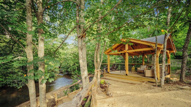 A wooden gazebo with a covered patio, surrounded by trees and a river. - Beautiful 2-bedroom cabin near Sparta and the Blue Ridge Parkway (Sparta)