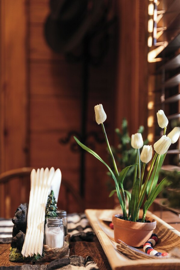 Une table en bois ornée d’une plante en pot, de bougies blanches et d’une figurine d’ours.