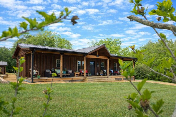 A wooden cabin with a porch, outdoor seating, and a well-maintained lawn.