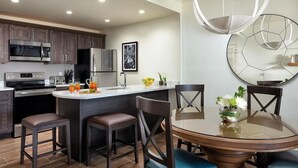 Une cuisine moderne avec des meubles en bois foncé, des appareils électroménagers en acier inoxydable et un îlot central doté de tabourets de bar.