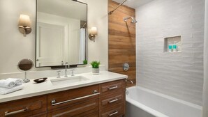 Une salle de bain moderne avec un meuble-lavabo en bois, un grand miroir, un lavabo et un espace douche.