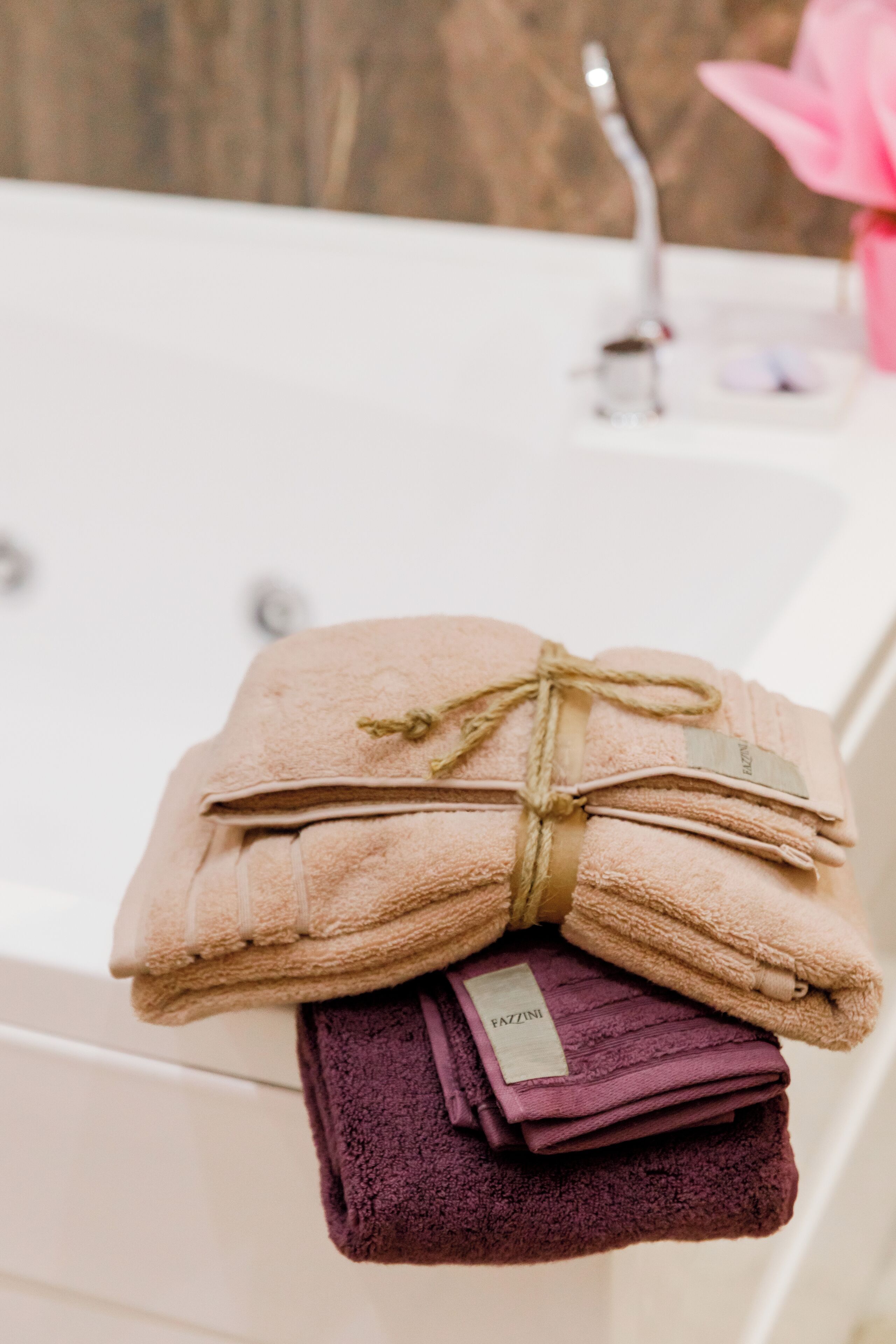 A stack of folded towels with a tag, placed on a white bathtub.