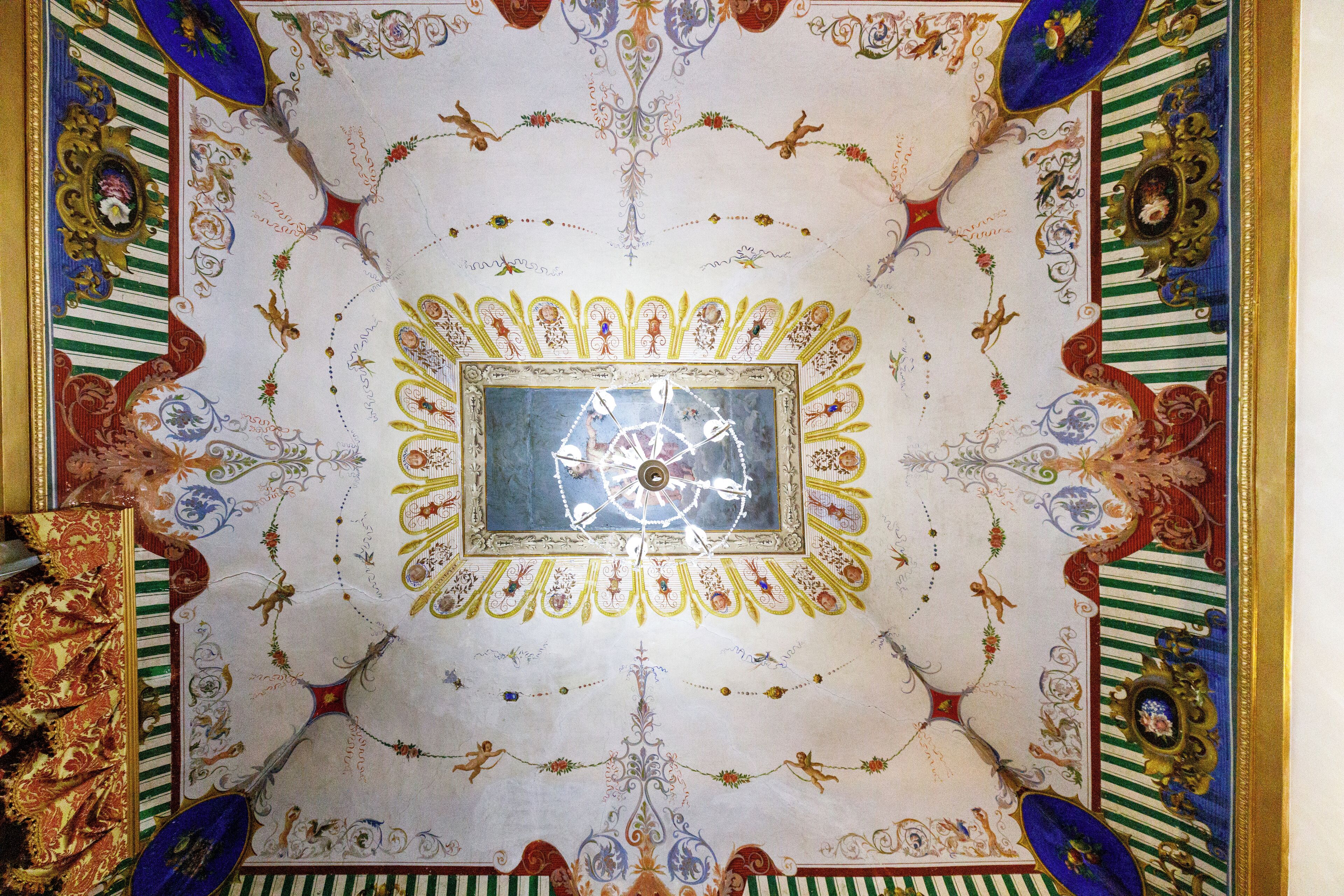 A ceiling with intricate designs and a central clock.