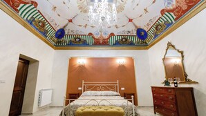 A bedroom with a bed, a dresser, a mirror, and a chandelier.