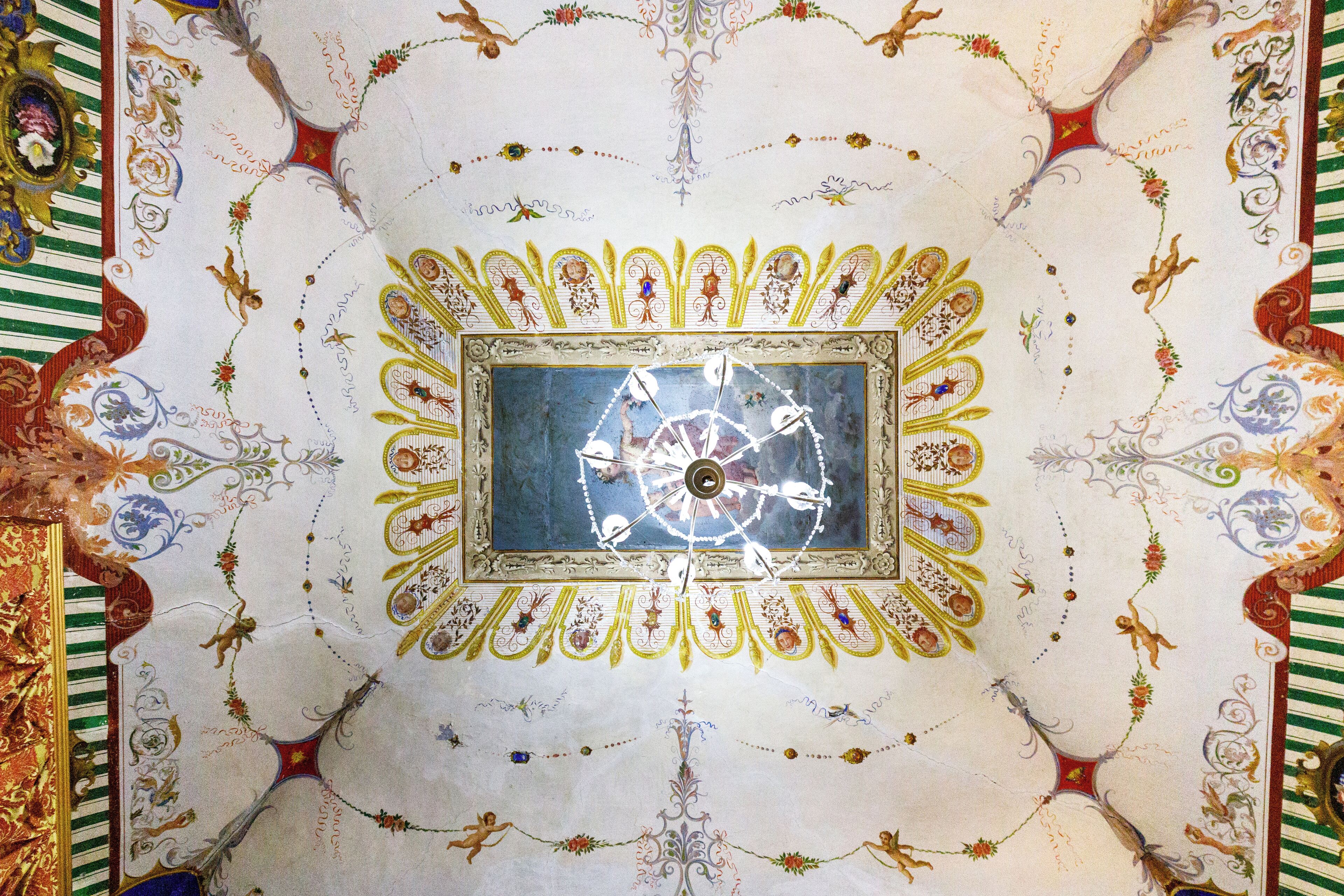 Un soffitto con un orologio centrale e decorazioni floreali elaborate.
