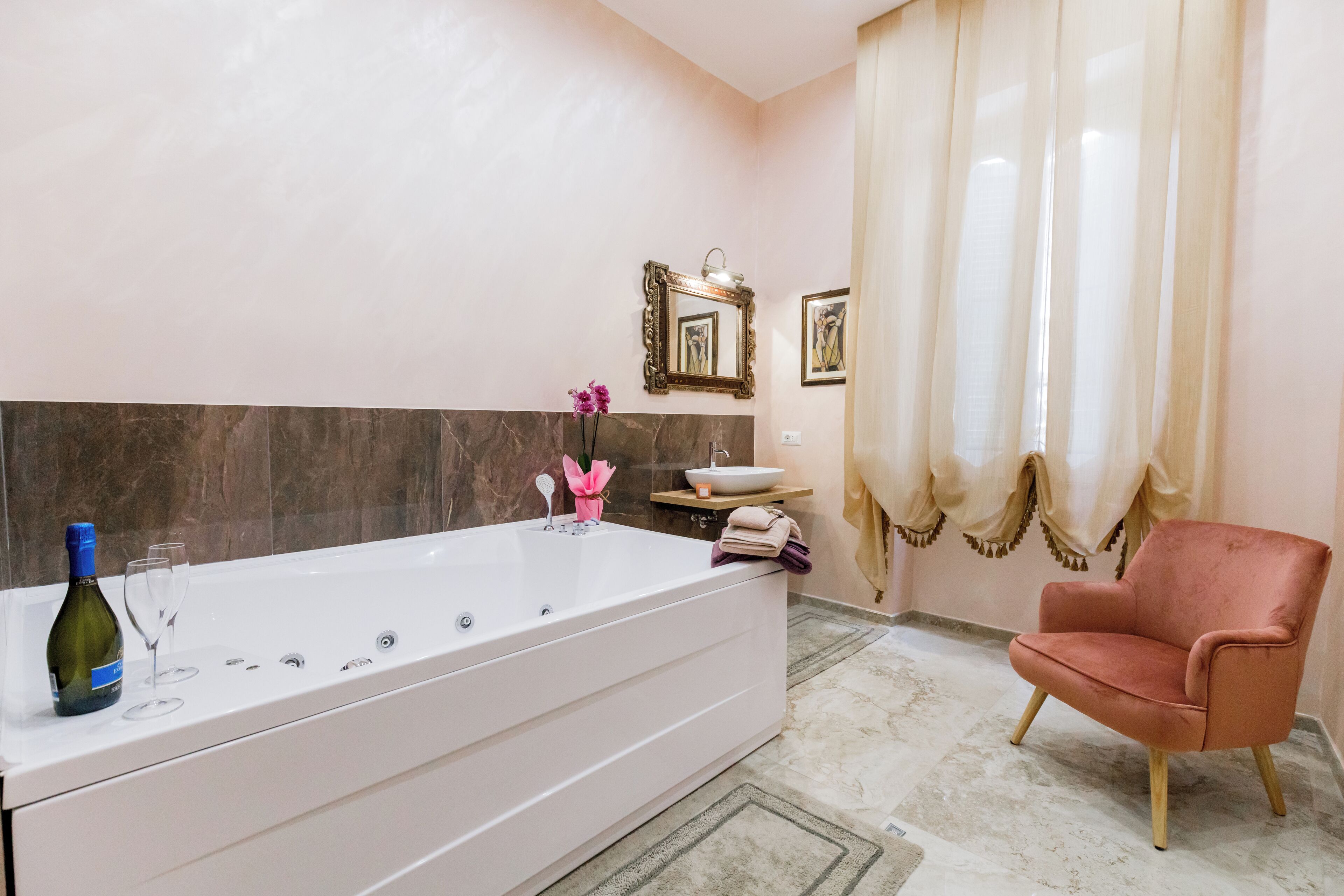 Un baño con una bañera grande, un tocador con espejo y una silla.