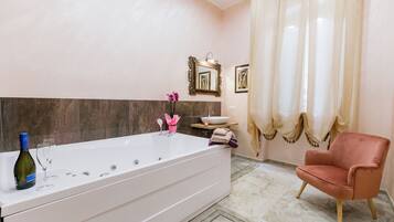 Un baño con una bañera grande, un tocador con espejo y una silla.