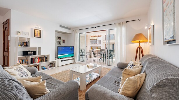En moderne stue med en grå sofa, et hvidt sofabord og en reol.