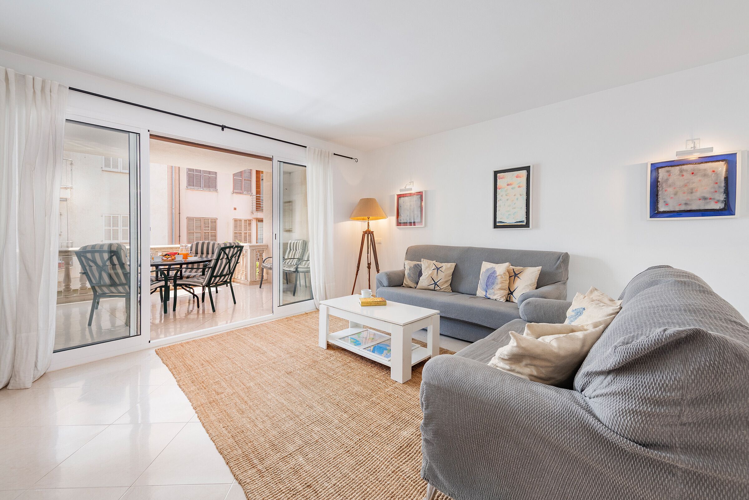 Una sala de estar moderna con un sofá gris, una mesa de centro blanca y un comedor con sillas y una mesa.