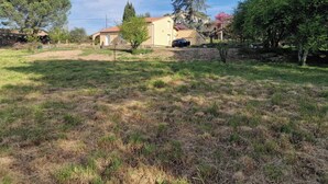 A residential area with a house, a parked car, and a grassy field. - The 3 arcades (Ucel)