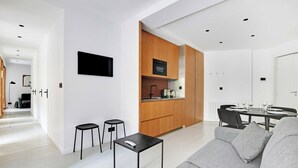 Eine moderne Küche mit Holzschränken, einem schwarzen Backofen und einem Essbereich mit Tisch und Stühlen.