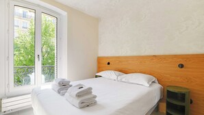 Ein Hotelzimmer mit Bett, Fenster mit Blick auf Grünflächen und einer Heizung.