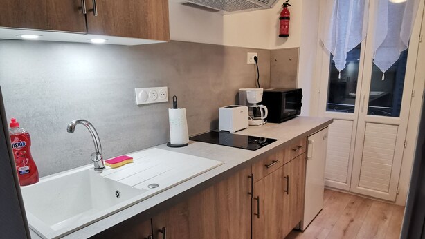 A modern kitchen with wooden cabinets, a white countertop, a sink, a coffee maker, a toaster, and a microwave. - Studio with bike room (Bagnères-de-Luchon)