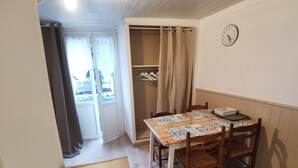 A dining area with a wooden table, four chairs, and a clock on the wall. - Studio with bike room (Bagnères-de-Luchon)