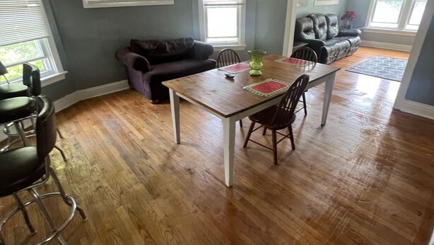 Een eetgedeelte met een houten tafel en stoelen, een plafondventilator en een bank.