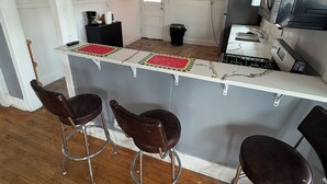 Een keuken met een bar, houten vloeren en een plafondventilator.