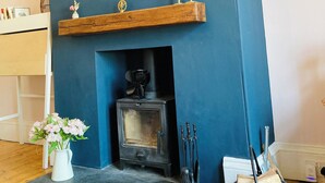 Une pièce avec un mur d’accent bleu, une cheminée surmontée d’un miroir et une étagère en bois avec des bougies.