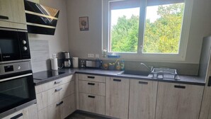 A modern kitchen with wooden cabinets, a Bosch oven, a toaster, and a window with a view of trees. - Comfortable gîte with spa and billiards near Beauval zoo (Saint-Aignan)