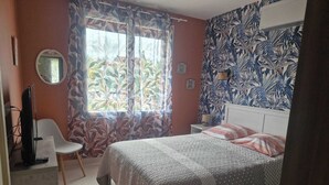 A bedroom with a bed, a chair, a TV, and a window with curtains. - Comfortable gîte with spa and billiards near Beauval zoo (Saint-Aignan)