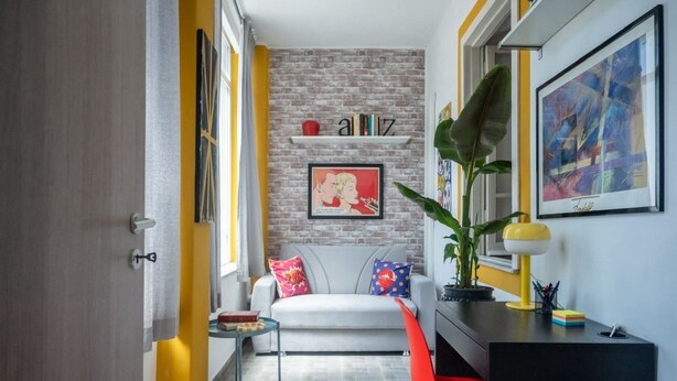 Una sala de estar moderna con una pared de ladrillo decorativa, un sofá blanco y una silla roja.