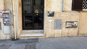 Entrada de un edificio con un amplio arco, una puerta negra con celosía metálica y un cartel sobre la puerta que indica 'VIA Q VIII Bartolino da Novara'.