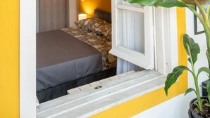 Una habitación con una cama, un ventanal y una planta en maceta.